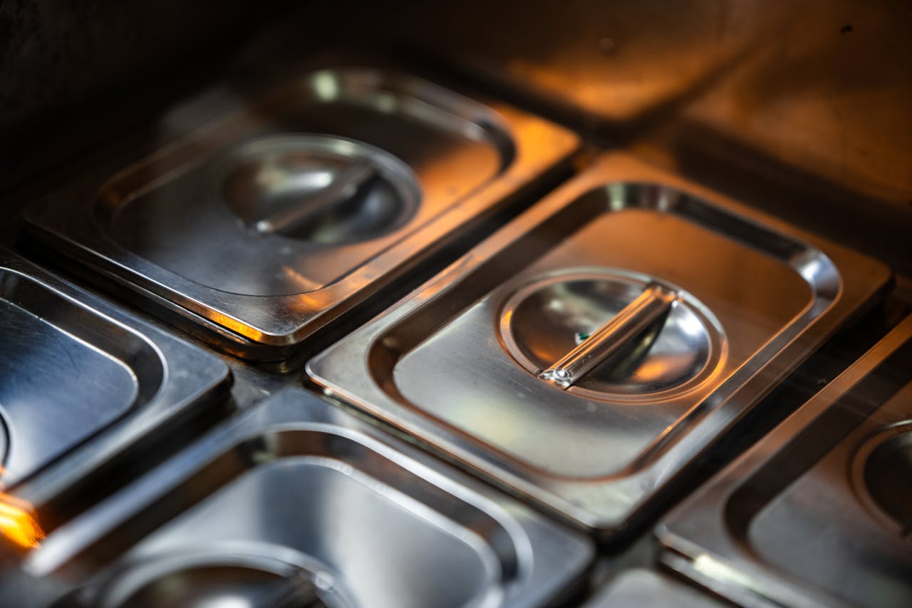 Stacks of shiny stainless steel food containers in a professional kitchen setting.